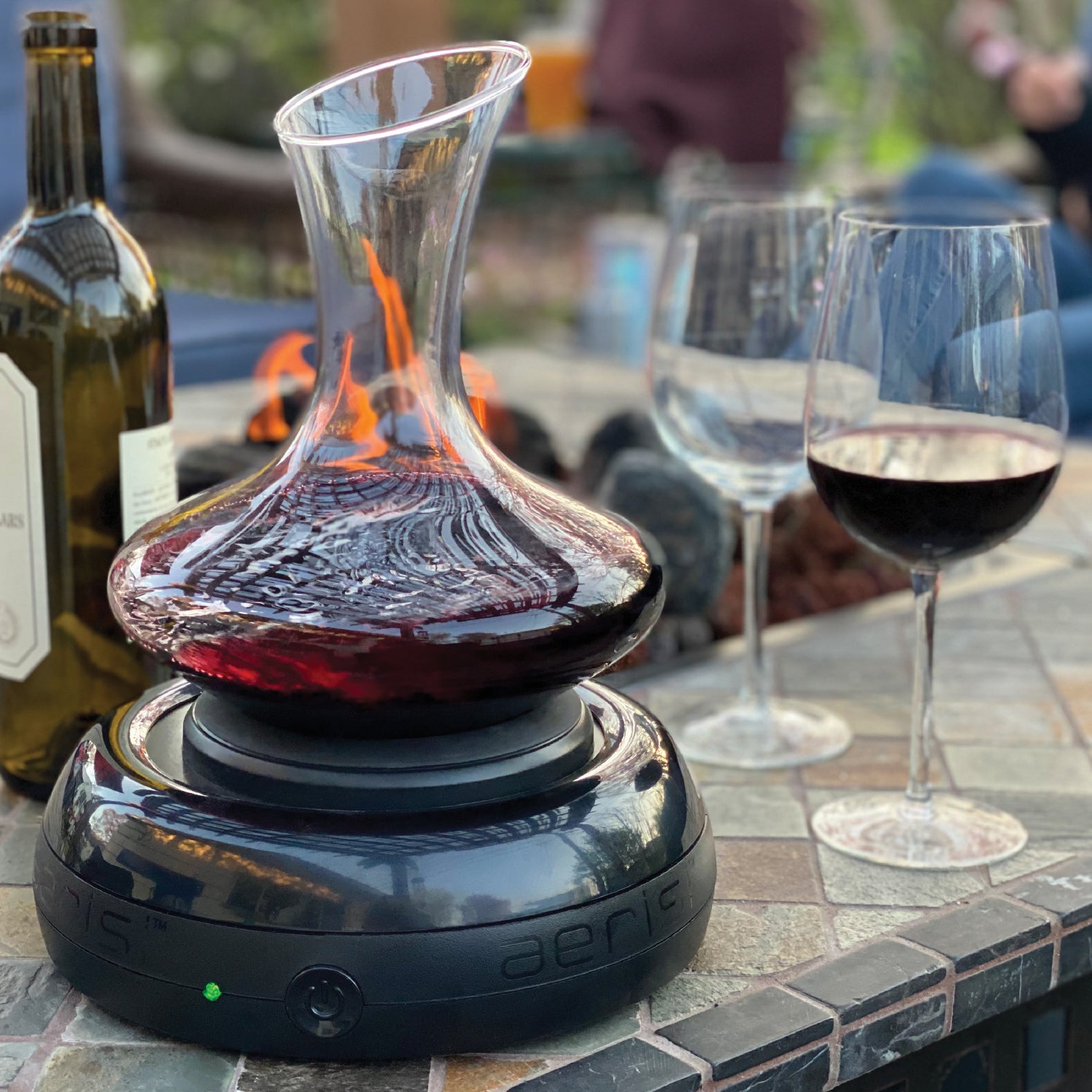 Aerisi Wine Aerator and Decanter with red wine on patio table with firepit